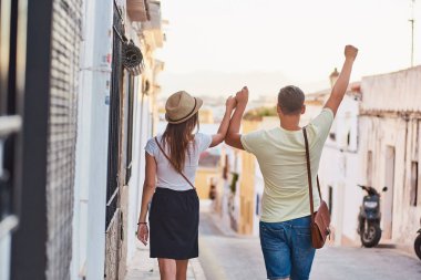 Eller yukarı ile mutlu genç çift arka. Erkek ve kadın tatile eski şehirde yürüyüş.