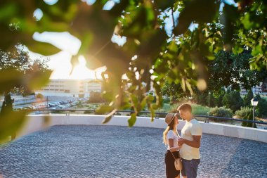 Elele ve birbirine sevgi gün güneşli yaz ile bakarak Genç mutlu bir çift. Ağaç yapraklarını arkasından fotoğraf.