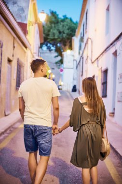 Eski binalar ile dar İspanyol sokak boyunca akşam yürüyüş aşık genç çiftin ters.