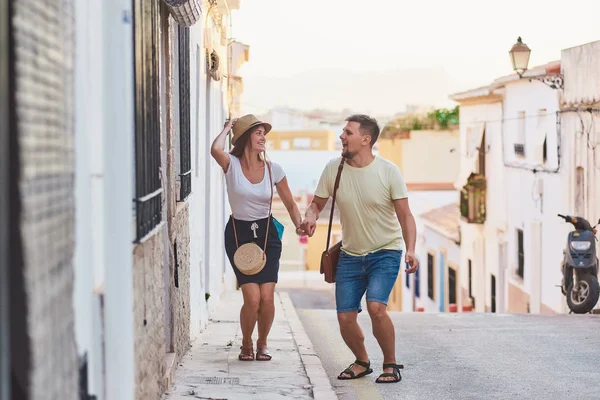 Happy and funny young couple of travellers jumping when walking in old Spanish town.