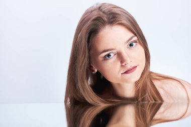 Genç güzel kadın gözleri iri ve doğal makyaj ışık gri arka plan üzerinde izole kamera bakıyor. Güzellik moda kız ayna yukarıda portresi. Yansıma.