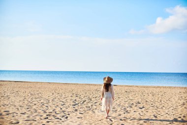 Tarafından deniz güneşli yaz günü sahilde yürüyüş hasır şapkalı güzel ve genç birbayan. Uzay kopyalayın. Seyahat ve Özgürlük kavramı.