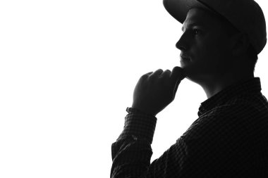 Yan yüzü düşünceli bir gencin şapkalı. Siluet. Siyah ve beyaz.