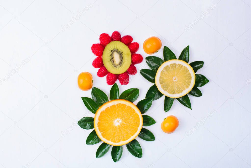 Flowers made of citrus fruits isolated on white. Orange, lemon, kiwi, tangerine and raspberry. Colorful and fresh composition.