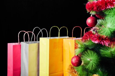 Birçok renkli alışveriş torbaları ve Noel ağacı siyah arka plan üzerine izole. Hediyeler ve tatil indirimler kavramı.