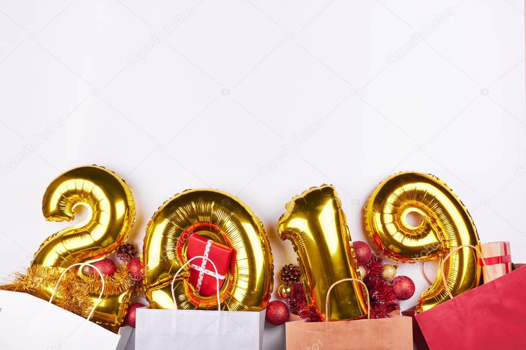 Golden New Year 2019 inflatable balloons with colorful shopping bags and presents isolated on white background. Christmas celebration and holidays discounts.