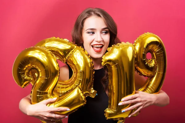 Kırmızı olan mutlu kadın portresi kutluyor yeni yıl ve sahip eğlenceli kırmızı zemin üzerine altın 2019 balonlu dudakları.