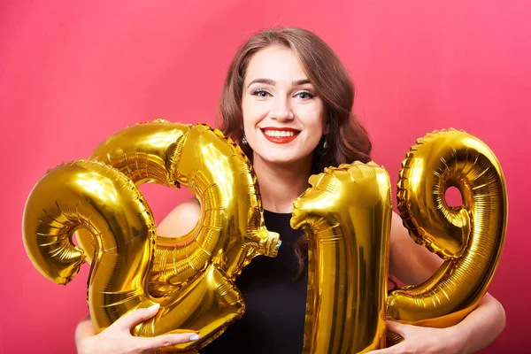 Kırmızı olan mutlu kadın portresi kutluyor yeni yıl ve sahip eğlenceli kırmızı zemin üzerine altın 2019 balonlu dudakları.