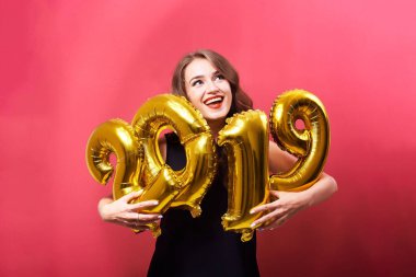 Yeni yıl 2019 kutluyor ve ellerinde kırmızı zemin üzerine altın balonlar tutan parlak kalıcı makyaj ile genç gülümseyen kadın.