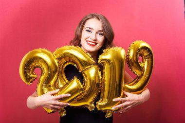 Yeni yıl 2019 kutluyor ve ellerinde kırmızı zemin üzerine altın balonlar tutan parlak kalıcı makyaj ile genç gülümseyen kadın.