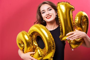 Yeni yıl 2019 kutluyor ve ellerinde kırmızı zemin üzerine altın balonlar tutan parlak kalıcı makyaj ile genç gülümseyen kadın.