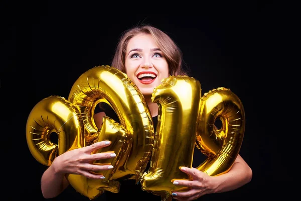 Eğleniyor ve altın balonlar siyah arka plan üzerine elinde tutan parlak makyaj olan komik bir kadın portresi. Yeni yıl 2019 kutlama.