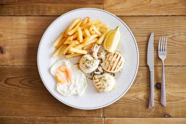 Yumurta ve mürekkep balığı ızgarada yapılan havai görünümü Fransız kızartması. Ahşap arka plan üzerinde beyaz tabak.