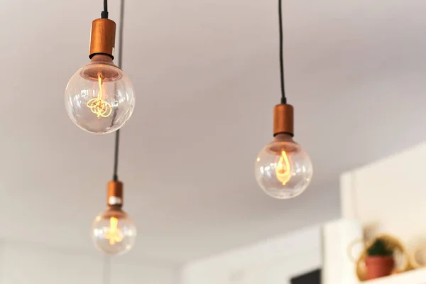 Vintage light bulbs hanging from the ceiling with white wall. Interior design.