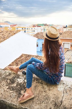 Arkadan genç uzun saçlı kadının küçük bir İspanyol şehrin panoramik görünüşü.