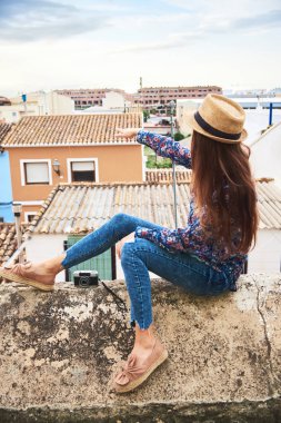 Bir şeye işaret ve küçük İspanyol şehrin panoramik manzarayı genç uzun saçlı kadın.