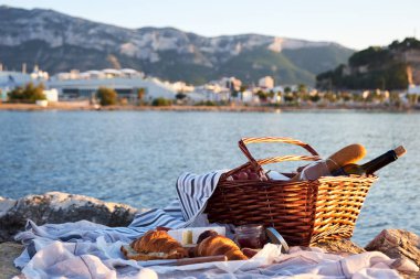 RomatiC piknik Denia, İspanya sahilde. Kırmızı şarap, ekmek, reçel, peynir ve jamon güneşli bir deniz ve kale arka plan üzerinde piknik sepeti.