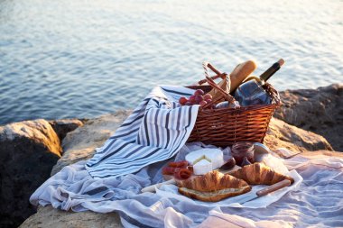 Kırmızı şarap, ekmek, reçel, peynir ve jamon güneşli bir piknik sepeti. Deniz arka plan üzerinde plaj romantik piknik.