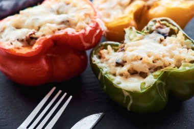 Pirinç, sebze ve siyah plaka üzerinde eritilmiş peynir ile renkli biber dolması Close-up.