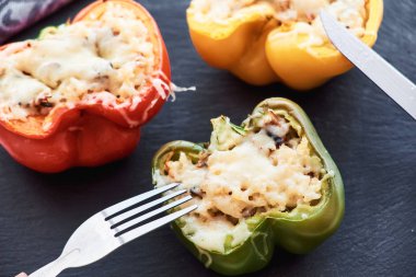 Pirinç, sebze ve siyah plaka üzerinde eritilmiş peynir ile renkli biber dolması Close-up.