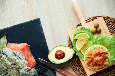 Ahşap tahta üzerinde bir lezzetli taze tuzlanmış somon fileto crispbread ve avokado ile en iyi görünümü. Aromatik otlar, baharatlar ve sebzeler - sağlıklı gıda, diyet ve pişirme kavramı.