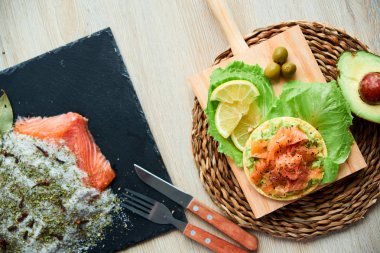 Ahşap tahta üzerinde bir lezzetli taze tuzlanmış somon fileto crispbread ve avokado ile en iyi görünümü. Aromatik otlar, baharatlar ve sebzeler - sağlıklı gıda, diyet ve pişirme kavramı.