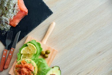 Ahşap tahta üzerinde bir lezzetli taze tuzlanmış somon fileto crispbread ve avokado ile en iyi görünümü. Aromatik otlar, baharatlar ve sebzeler - sağlıklı gıda, diyet ve pişirme kavramı.