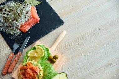 Ahşap tahta üzerinde bir lezzetli taze tuzlanmış somon fileto crispbread ve avokado ile en iyi görünümü. Aromatik otlar, baharatlar ve sebzeler - sağlıklı gıda, diyet ve pişirme kavramı.