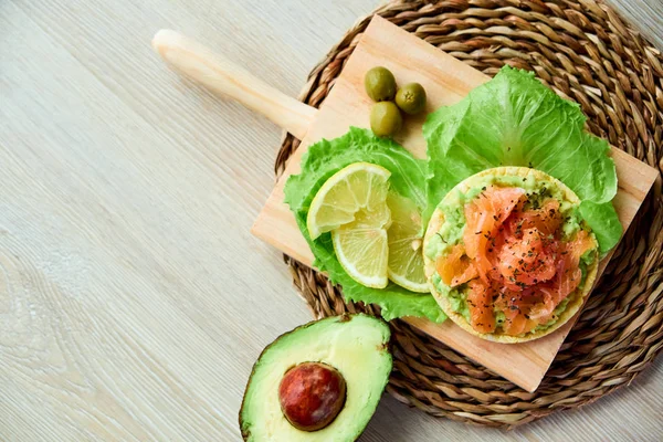 Ahşap tahta üzerinde bir lezzetli taze tuzlanmış somon fileto crispbread ve avokado ile en iyi görünümü. Aromatik otlar, baharatlar ve sebzeler - sağlıklı gıda, diyet ve pişirme kavramı.