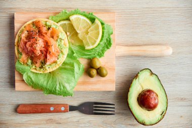 Ahşap tahta üzerinde bir lezzetli taze tuzlanmış somon fileto crispbread ve avokado ile en iyi görünümü. Aromatik otlar, baharatlar ve sebzeler - sağlıklı gıda, diyet ve pişirme kavramı.