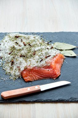 Aromatik otlar, baharatlar ve sebzeler siyah plaka üzerinde taze tuzlanmış somon fileto lezzetli kısmı. Sağlıklı gıda, diyet veya pişirme kavramı.