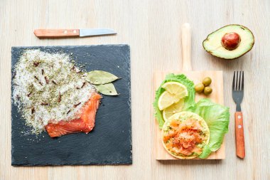 Ahşap tahta üzerinde bir lezzetli taze tuzlanmış somon fileto crispbread ve avokado ile en iyi görünümü. Aromatik otlar, baharatlar ve sebzeler - sağlıklı gıda, diyet ve pişirme kavramı. Mükemmeliyetçilik.