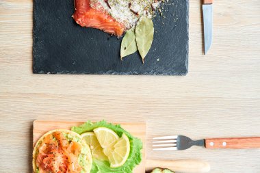 Ahşap tahta üzerinde bir lezzetli taze tuzlanmış somon fileto crispbread ve avokado ile en iyi görünümü. Aromatik otlar, baharatlar ve sebzeler - sağlıklı gıda, diyet ve pişirme kavramı. Mükemmeliyetçilik.