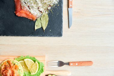 Ahşap tahta üzerinde bir lezzetli taze tuzlanmış somon fileto crispbread ve avokado ile en iyi görünümü. Aromatik otlar, baharatlar ve sebzeler - sağlıklı gıda, diyet ve pişirme kavramı. Mükemmeliyetçilik.