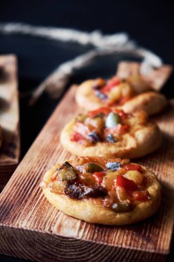 Geleneksel İspanyolca Close-up mini pizza cocas ahşap tahta üzerinde pişmiş. Siyah arka plan.