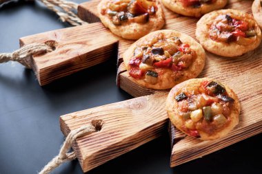 Geleneksel İspanyolca Close-up mini pizza cocas ahşap tahta üzerinde pişmiş. Siyah arka plan.