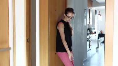 Dairesini kapılarını açıyor genç çekici kadın gözlük, çanta ve anahtarları yere atma, uygun olmayan yüksek topuklu ayakkabılarını alarak ve çömelme işten eve geliyor yorgun.