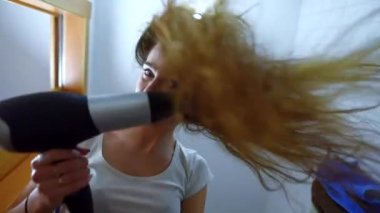 Genç çekici kadın bir banyoda saç kurutma