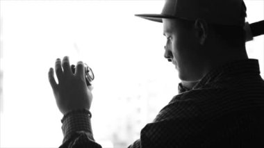 Tek renkli siluet bir kamera objektifi içinde seyir ve bir el feneri ile vurgulayarak şapkalı bir genç adam fotoğrafçı. Ağır çekim, kroki, izole.