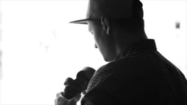 Tek renkli siluet lens kapağı alarak ve içinde seyir şapkalı bir genç adam fotoğrafçı. Ağır çekim, kroki, izole.