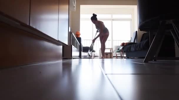 Jonge aantrekkelijke huisvrouw stofzuigen in de kamer — Stockvideo