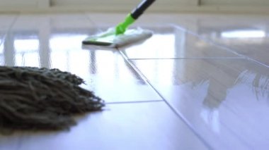 Genç kadın beyaz karo zemin paspas ile evde silme