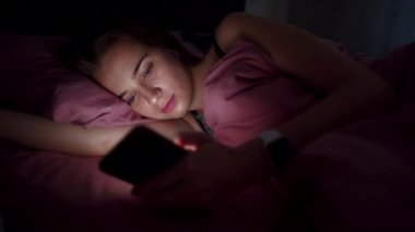 Cep telefonu gece yatakta olan kadın