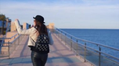 Mutlu genç çekici kız blogger siyah şapka ve yuvarlak güneş gözlüğü takmış gülümseyen ve denizin kalktıktan ve güneş gözlüğü üzerinde koyarak iyi bir hava zevk. Denia, İspanya.