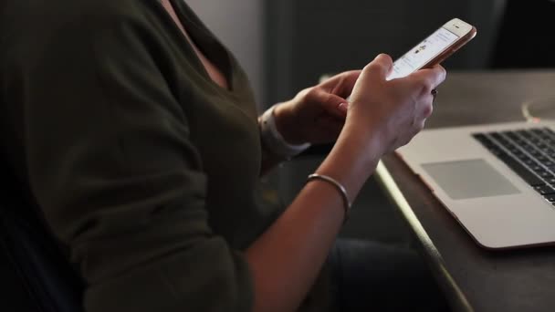 Woman using a smartphone with laptop on background — Stock Video