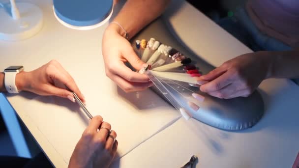 Крупный план женских рук, выбирающих цвет для маникюра — стоковое видео