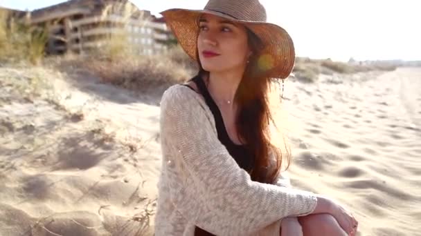 Νεαρή γυναίκα φοράει χαλαρωτικό ψάθινο καπέλο στην παραλία — Αρχείο Βίντεο