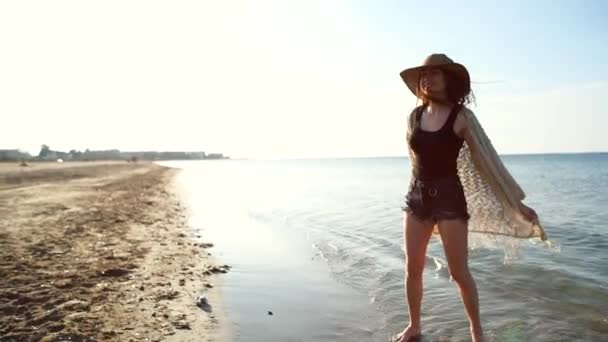 Ung kvinna bär stråhatt njuter och dans vid havet — Stockvideo