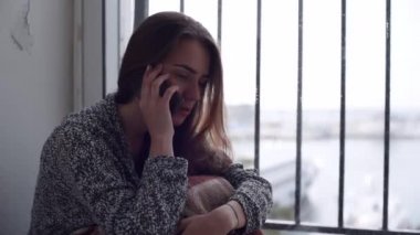 Genç çekici kadın gülüyor sonunda cep telefonla konuşuyor. Cam kenarında oturan yalnız despessed kadın.