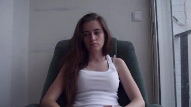 Genç bitkin depresif kadın bir sandalyede oturuyor ve cam kenarında duygusal sıkıntı acı. Yalnız kadın intihar düşünceleri ile umutsuzluk içinde.